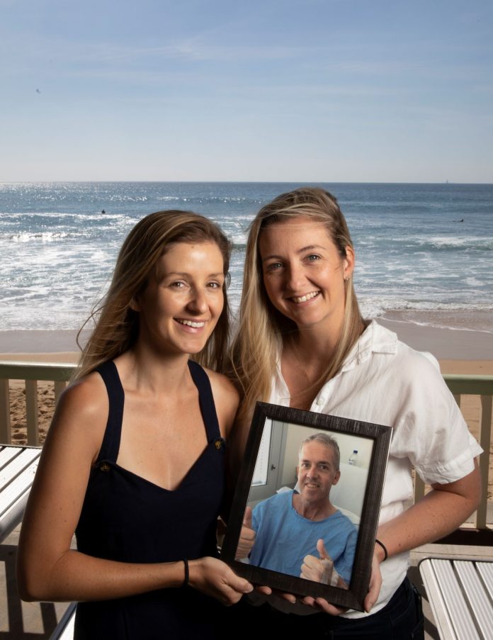 two women in front of the beach holding a photo of their father