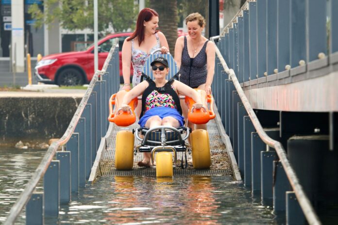 Carers assist Tracey Blair as she prepares to enter the water.