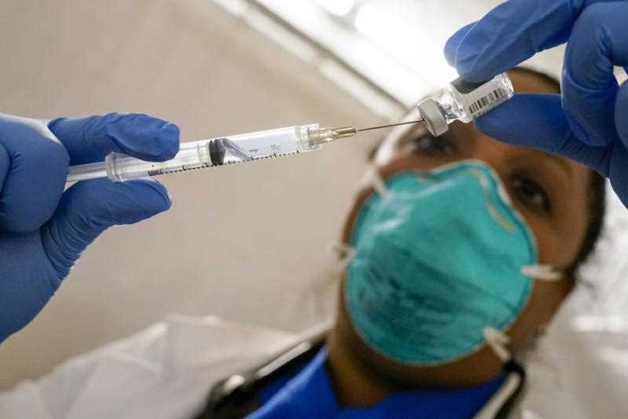 a doctor extracts the Pfizer COVID-19 Vaccine out of a vial
