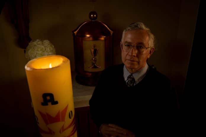 Father Greg Barker with a candle