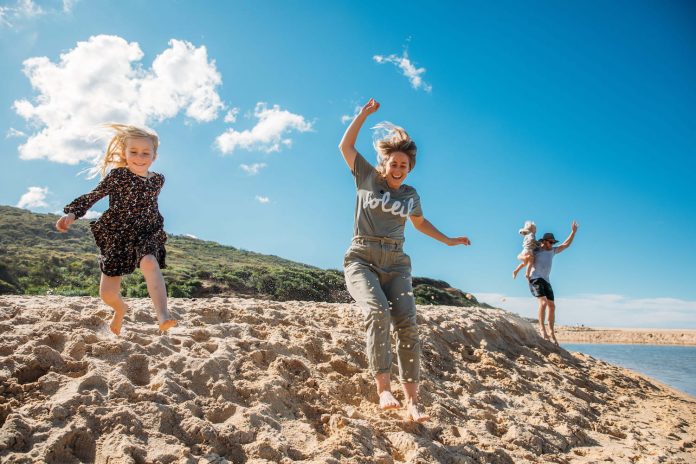 A family jumping in the sand at Glenrock in Lake Macquarie
