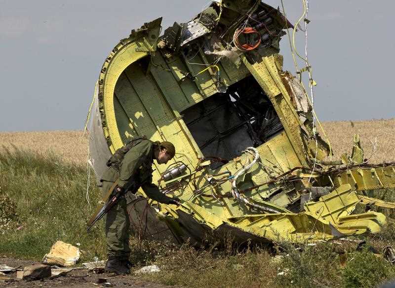 In this July 22, 2014 file photo, a pro-Russian rebel touches the MH17 wreckage at the crash site of Malaysia Airlines Flight 17, near the village of Hrabove, eastern Ukraine.
