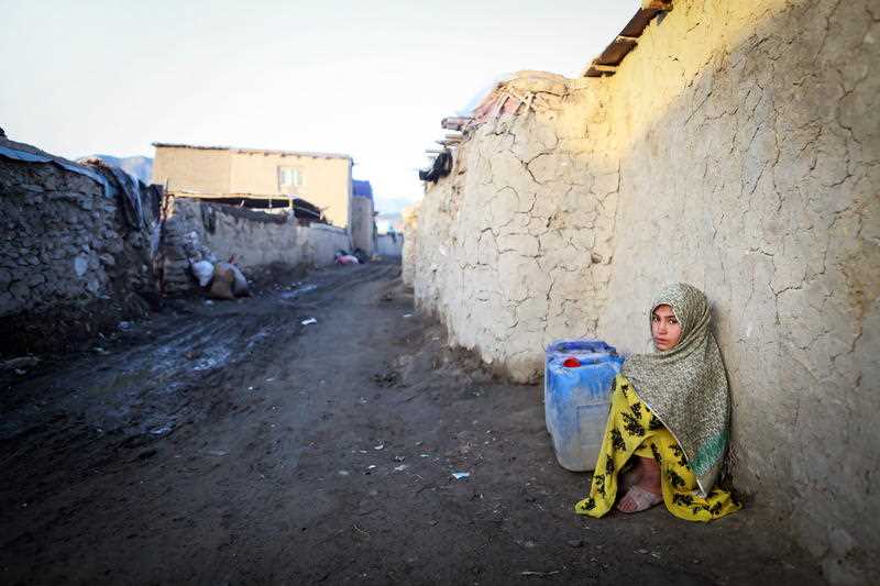 An internally displaced Afghan girl waits with water containers to be filled from a tanker outside of her temporary shelter in Kabul, Afghanistan, 29 April 2020
