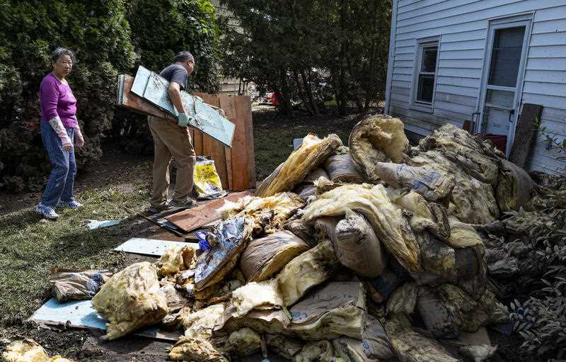 Two residents of New Jersey removing piles of storm debris from their home
