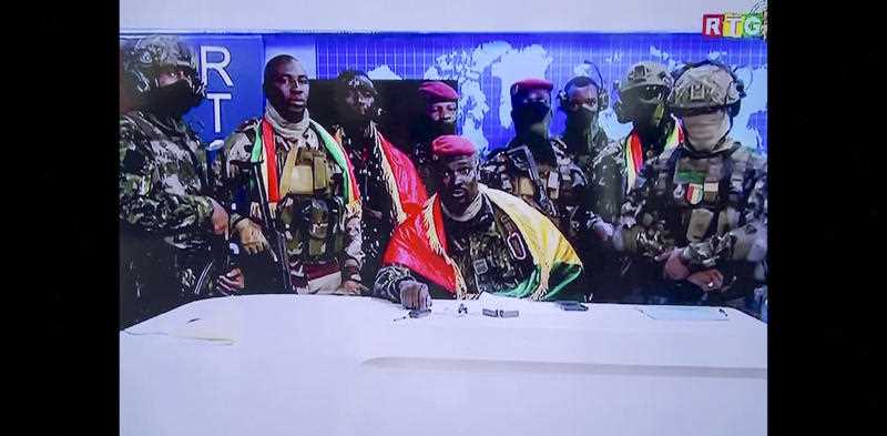 In this image made from video, Col. Mamadi Doumbouya, center, commander of the army's special forces unit, surrounded by others and draped in a Guinean flag, makes an address to the nation from state television headquarters in the capital Conakry, Guinea