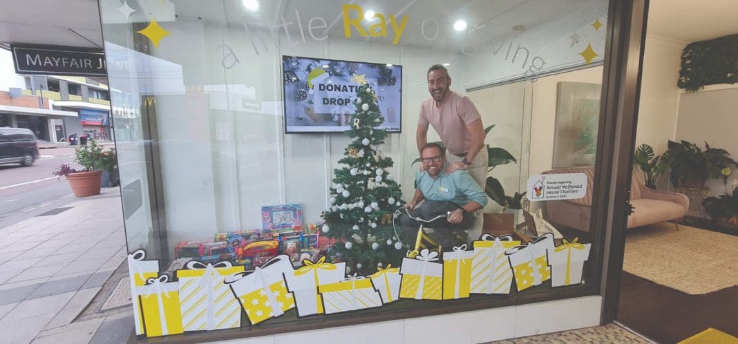 Ty Zink and Troy McLennan near the Christmas tree in their office window