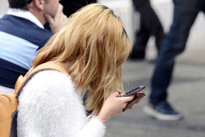 A young woman looks at her mobile phone