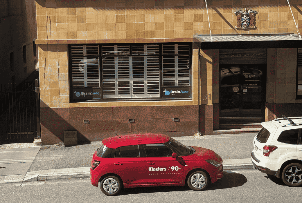 red suzuki swift parked on street in city.